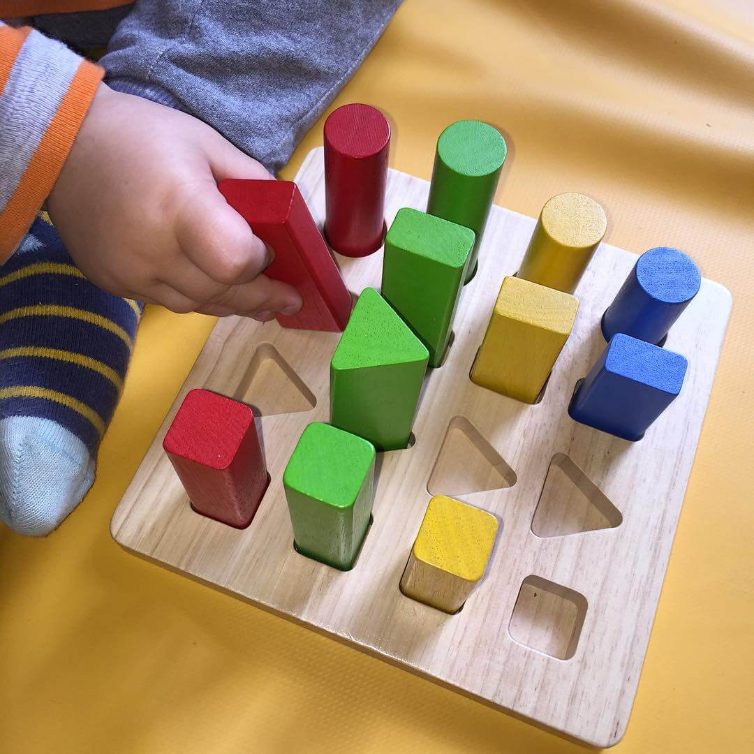 تصویر کودک در حال بازی با صفحه اشکال هندسی
